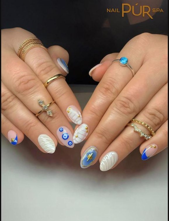 White shell-textured nails with a blue evil-eye and gold details
